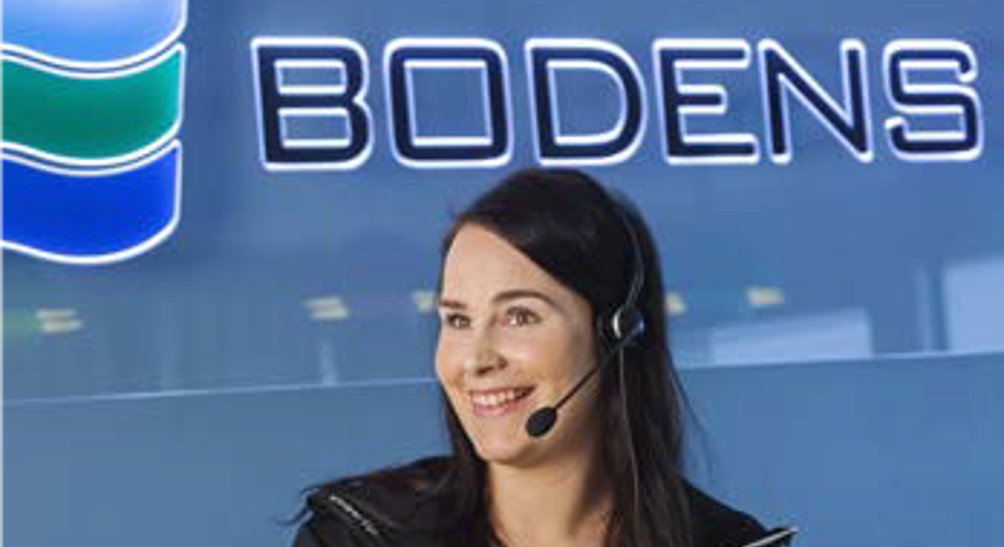 Tjej med telefonheadset framför blå vägg med Bodens Energis logotyp