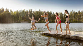 Fyra flickor på en brygga, två hoppar ned i vattnet