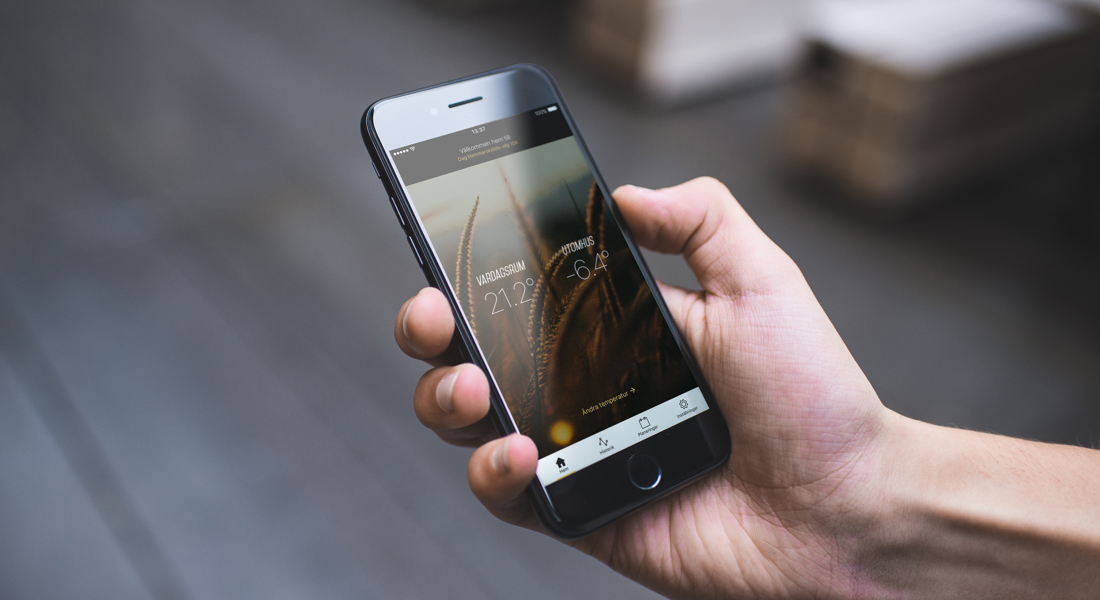 En hand som håller i en mobiltelefon som visar inom- och utomhustempratur. Foto